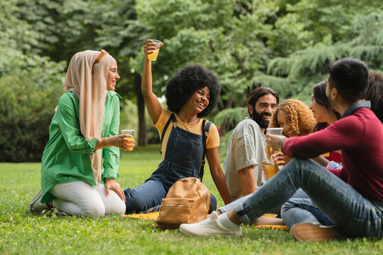 Multiracial friends having fun together drinking beer and laughing outdoors.