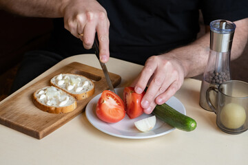 Making sandwich. Men hands preparing snack. Human cuts tomato. Process of preparing snacks. Sandwich with sauce and vegetables. Hands of male cook. Man prepares food. Sandwich recipe. Culinary skill