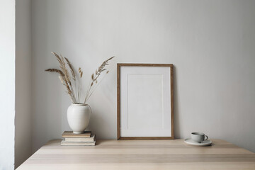Elegant neutral poster mockup. Wooden picture frame mockup on beige table. Vase with dry grass and...