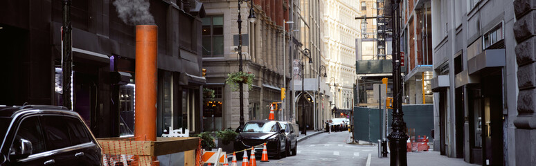 steaming ventilation pipe near cars on narrow street in new york city, metropolis atmosphere, banner