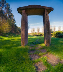 Stone arch in the spring park against blue sky background. Picturesque morning scene of green meadow in botanical garden. Beauty of nature concept background.