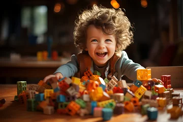 Foto op Canvas A little boy laughs merrily and plays with a colorful, bright construction set. Happy satisfied child with curly hair and a beautiful smile. Lots of colorful Bricks pieces. A fun, educational game. © Eugenia