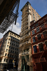 Fototapeta na wymiar building with fire escape stairs on autumnal street in downtown of new york city, low angle view