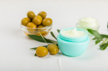 Jar of natural olive cream with olive oil extract on a texture background. Cosmetic tube. Moisturizing cosmetic cream for skin. Body care. Beauty concept. Copy space. Flat lay. Hand cream.