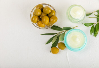 Jar of natural olive cream with olive oil extract on a texture background. Cosmetic tube. Moisturizing cosmetic cream for skin. Body care. Beauty concept. Copy space. Flat lay. Hand cream.