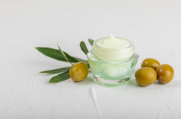 Jar of natural olive cream with olive oil extract on a texture background. Cosmetic tube. Moisturizing cosmetic cream for skin. Body care. Beauty concept. Copy space. Flat lay. Hand cream.