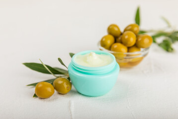 Jar of natural olive cream with olive oil extract on a texture background. Cosmetic tube. Moisturizing cosmetic cream for skin. Body care. Beauty concept. Copy space. Flat lay. Hand cream.