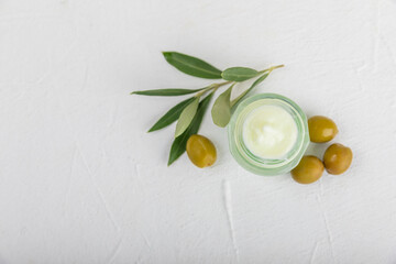 Jar of natural olive cream with olive oil extract on a texture background. Cosmetic tube. Moisturizing cosmetic cream for skin. Body care. Beauty concept. Copy space. Flat lay. Hand cream.