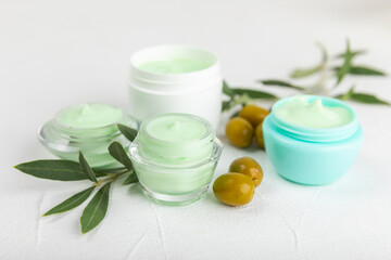 Obraz na płótnie Canvas Jar of natural olive cream with olive oil extract on a texture background. Cosmetic tube. Moisturizing cosmetic cream for skin. Body care. Beauty concept. Copy space. Flat lay. Hand cream.