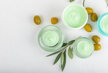 Jar of natural olive cream with olive oil extract on a texture background. Cosmetic tube. Moisturizing cosmetic cream for skin. Body care. Beauty concept. Copy space. Flat lay. Hand cream.
