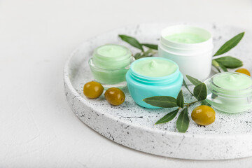 Fototapeta na wymiar Jar of natural olive cream with olive oil extract on a texture background. Cosmetic tube. Moisturizing cosmetic cream for skin. Body care. Beauty concept. Copy space. Flat lay. Hand cream.