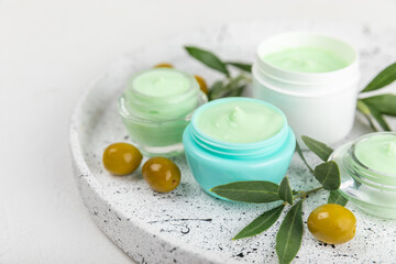 Jar of natural olive cream with olive oil extract on a texture background. Cosmetic tube. Moisturizing cosmetic cream for skin. Body care. Beauty concept. Copy space. Flat lay. Hand cream.