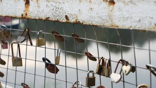 Rusting love locks on a metal bridge. Close-up of symbolic relationship padlocks, in 4K