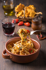 Italian cuisine: close-up forkful of spaghetti cooked with tomato and chanterelles. Vegetarian dish