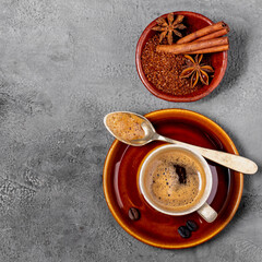 espresso coffee in cup, flavored with cinnamon and star anise, top view on gray textured background