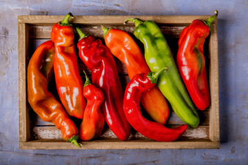 horn peppers, ripe and multicolored arranged on a wooden tray.