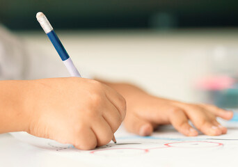 A creative kid coloring the shapes in coloring book with pencil. Coloring Book Education Talent Concept.