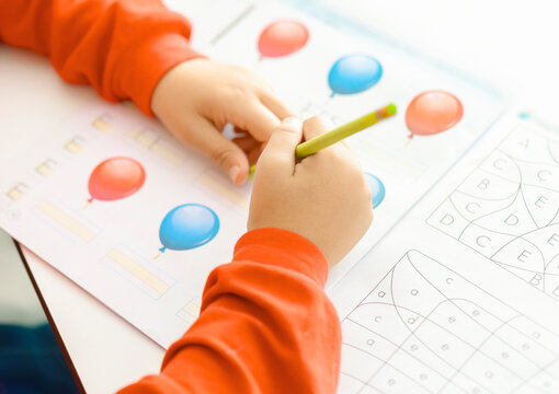 A creative kid coloring the shapes in coloring book with pencil. Coloring Book Education Talent Concept.