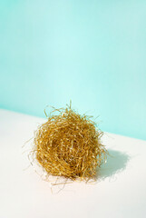 Golden ball with tinsels on a blue background beige table with shadow. Minimal winter holidays concept. Copy space. Space for text
