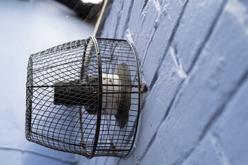 Shallow focus of a gas central heating duct seen attached to a recently painted English cottage outside wall. A cage protects the vent as it gets hot during use.