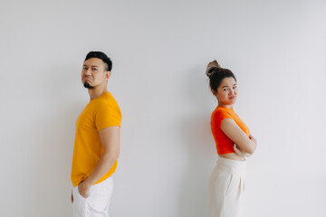 Asian Thai couple lover wear yellow and orange with grumpy face, standing back to back, get mad and...
