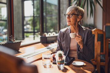 Mature woman is sitting in cafe and relaxing.