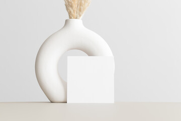 Square invitation card mockup with a pampas decoration on the beige table. 5x7 ratio, similar to A6, A5.