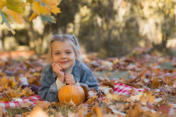 Portrait of a little girl 4 years old outdoors. A happy child in an autumn park with pumpkins. Happy childhood and fatherhood.