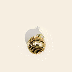 Christmas minimal card with golden mirror ball on beige background with beautiful shadow and glare. Shiny disco ball as Christmas toy. New Year concept, aesthetic celebration poster, trend xmas