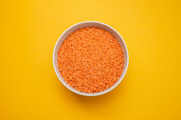 uncooked Red lentils in white bowl on ceramic