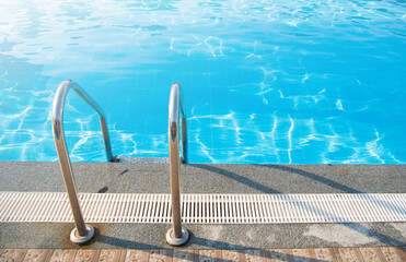 Grab bars ladder in the blue swimming pool