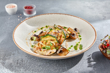 Side view of a grilled turkey fillet steak served with zucchini, mushrooms, and green sauce on a white ceramic plate. Presented on a gray concrete background, ideal for a fitness menu.