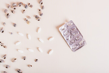 Concept of sunscreen supplements for skin, empty blister and shells on a light background