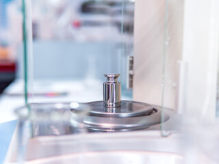 Analytical balance in a laboratory with a metal weight. Concept of laboratory balance calibration.