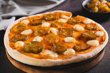 Pizza with pickles and mozzarella on a wooden board on the table