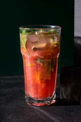 Strawberry-basil lemonade in a glass, a delightful fusion of sweet and herby flavors against a stark black backdrop
