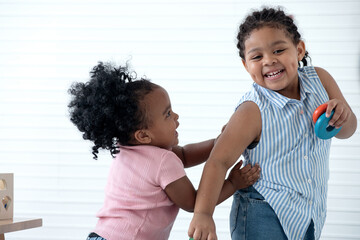 African siblings play happily chasing each other in room, group learning concept