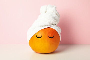 Skin and face care concept - pumpkin with eyelashes and towel - obrazy, fototapety, plakaty