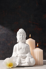 Buddha statue, candles and flower on dark background
