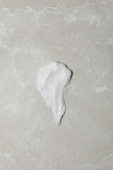 Cream drop on gray background, top view