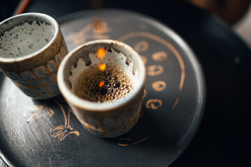 Black coffee is being poured into a ceramic mug.