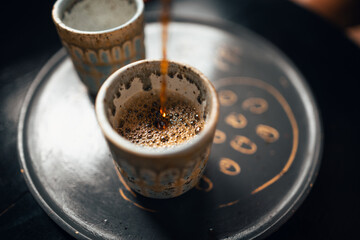 Black coffee is being poured into a ceramic mug.