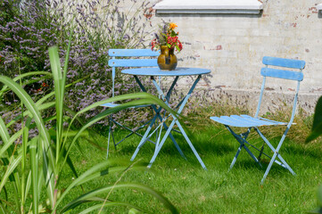gemütliche und einladende Sitzecke mit hellblauen Gartenmöbeln in einem wilden Garten