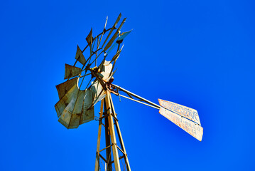 An old windmill against a clear blue sky.