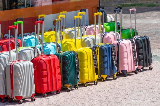 Colorful new different suitcases displayed in a row for sale in a store selection assortment.