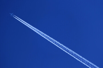 Airplane in the blue sky with white contrails