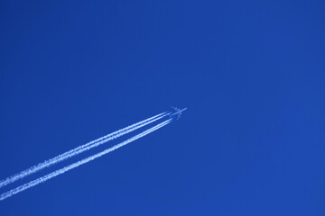Airplane in the blue sky with white contrails