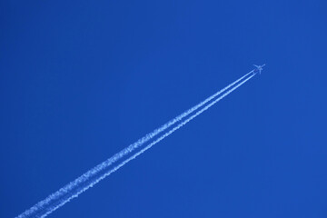 Airplane in the blue sky with white contrails