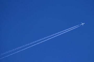Airplane in the blue sky with white contrails - obrazy, fototapety, plakaty