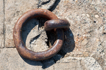 Rusty old mooring loop on textured stone background. Top view.